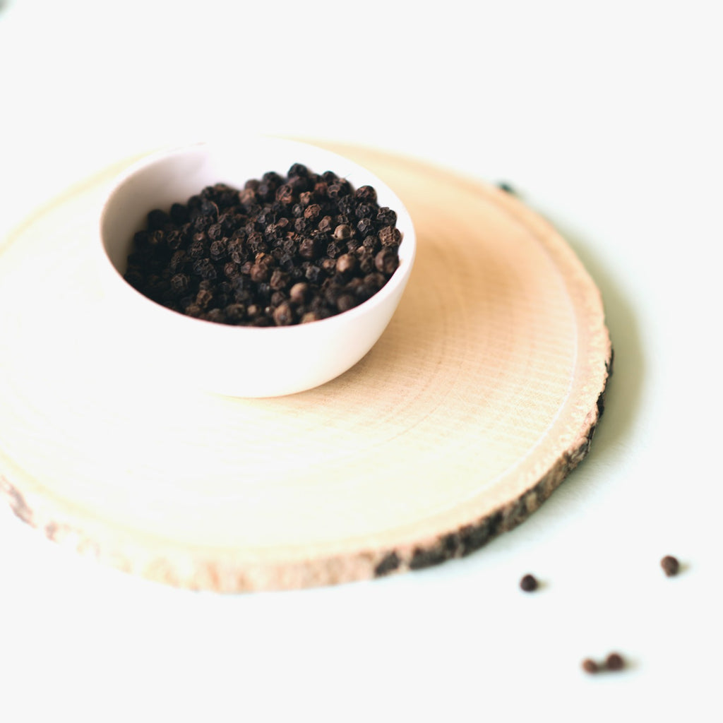 Bowl of black cumin seeds used to press black seed oil, white background