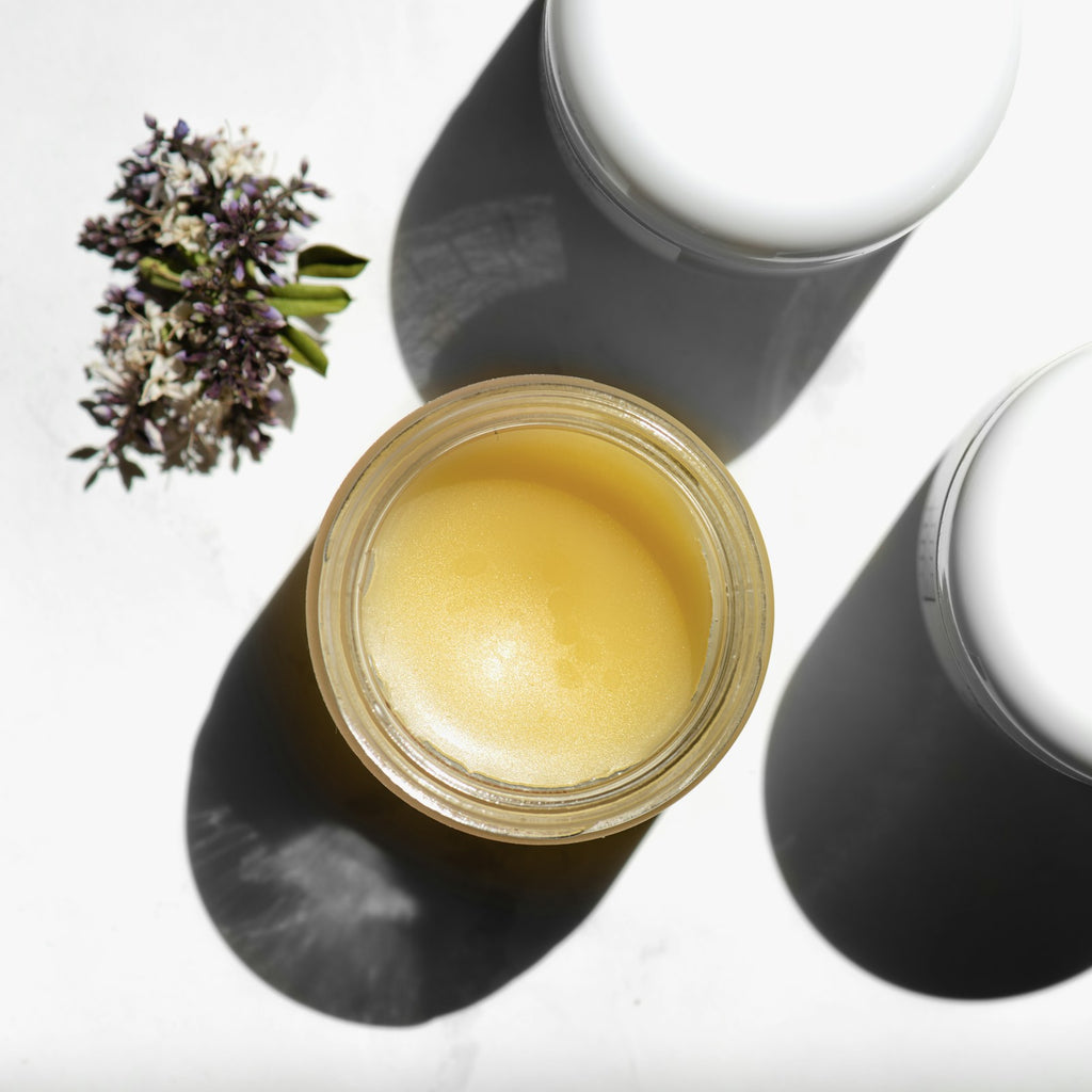 Open jar of shea butter balm on a white background