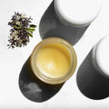 Open jar of shea butter balm on a white background