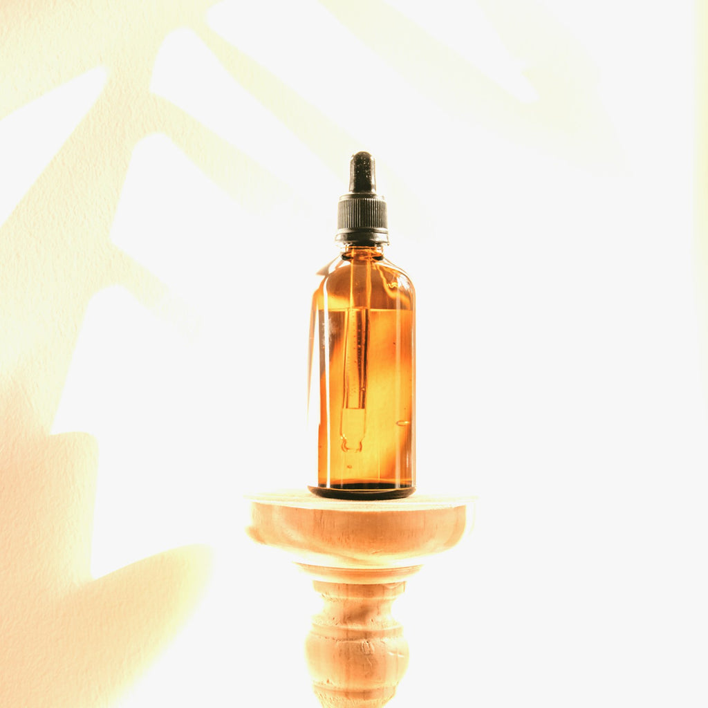 Amber glass dropper bottle of jojoba oil on a white studio background