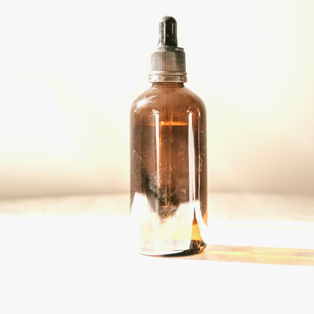 Amber glass witch hazel toner bottle with dropper cap on a white background