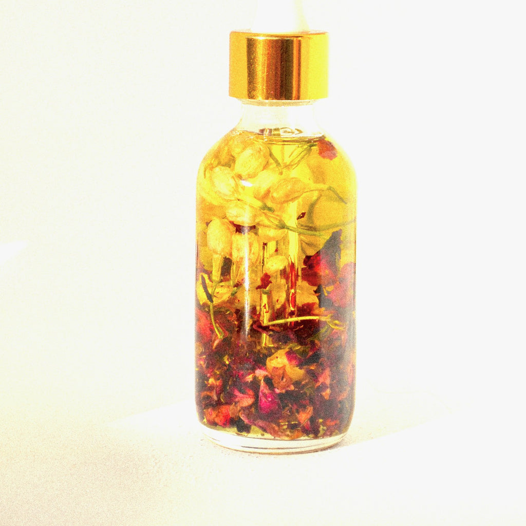 Calendula oil in a small glass bottle with flower petals, white studio background