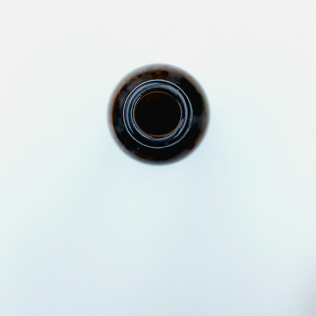 Dark glass bottle of black seed oil on a white background