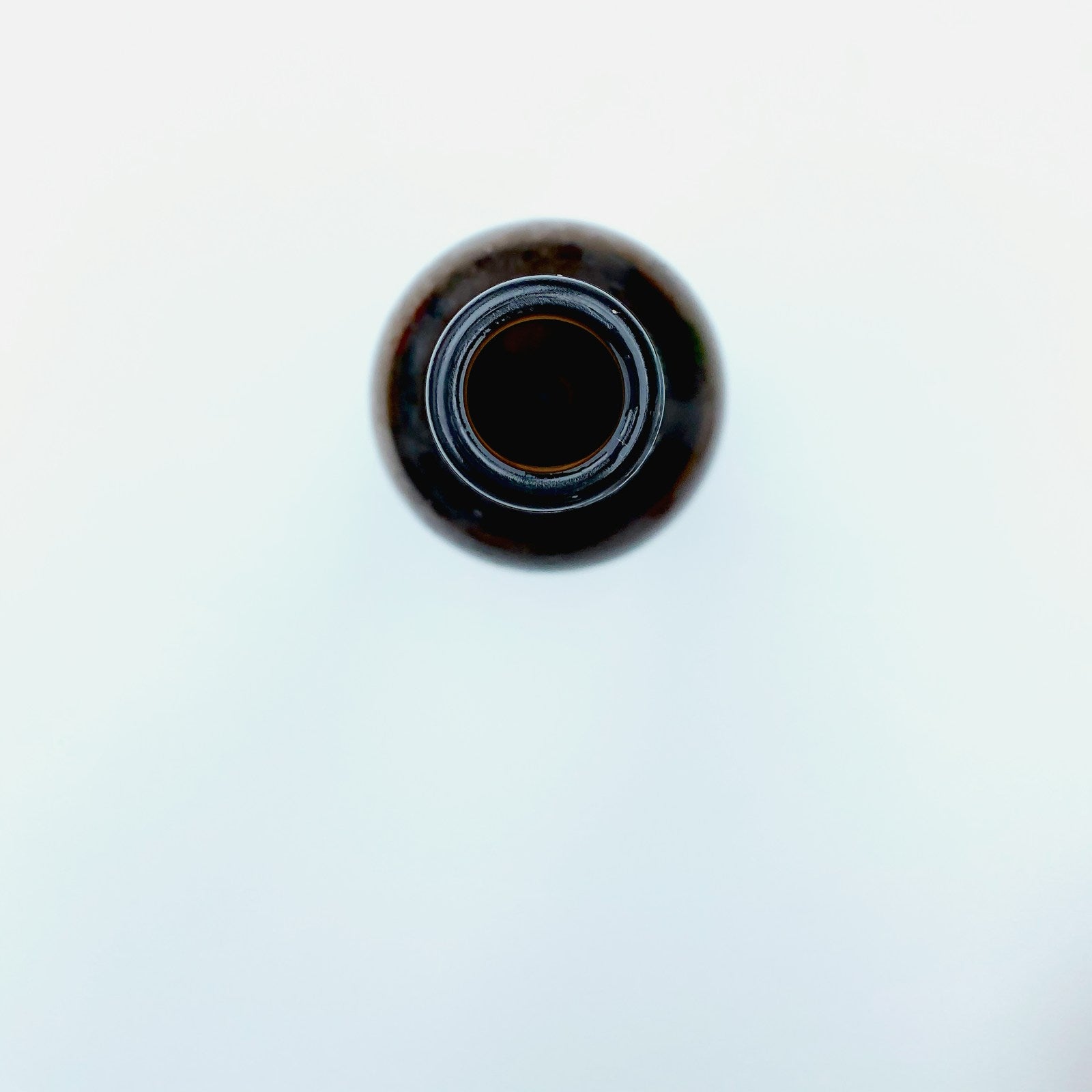 Dark glass bottle of black seed oil on a white background