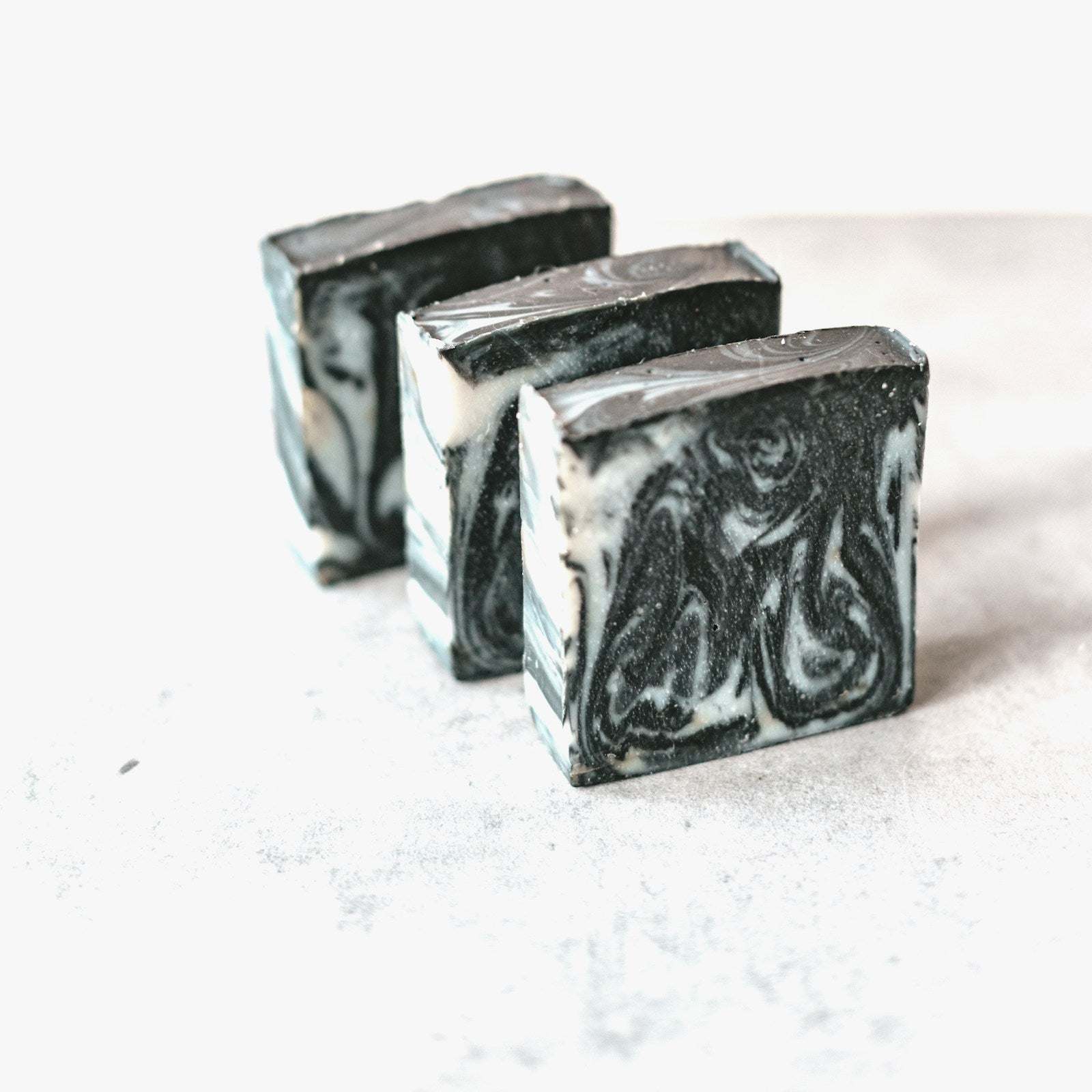 Activated charcoal soap bars with marbled black and white swirl on a white background
