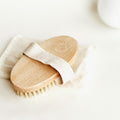 Wooden dry body brush with natural bristles and cotton strap on a white background