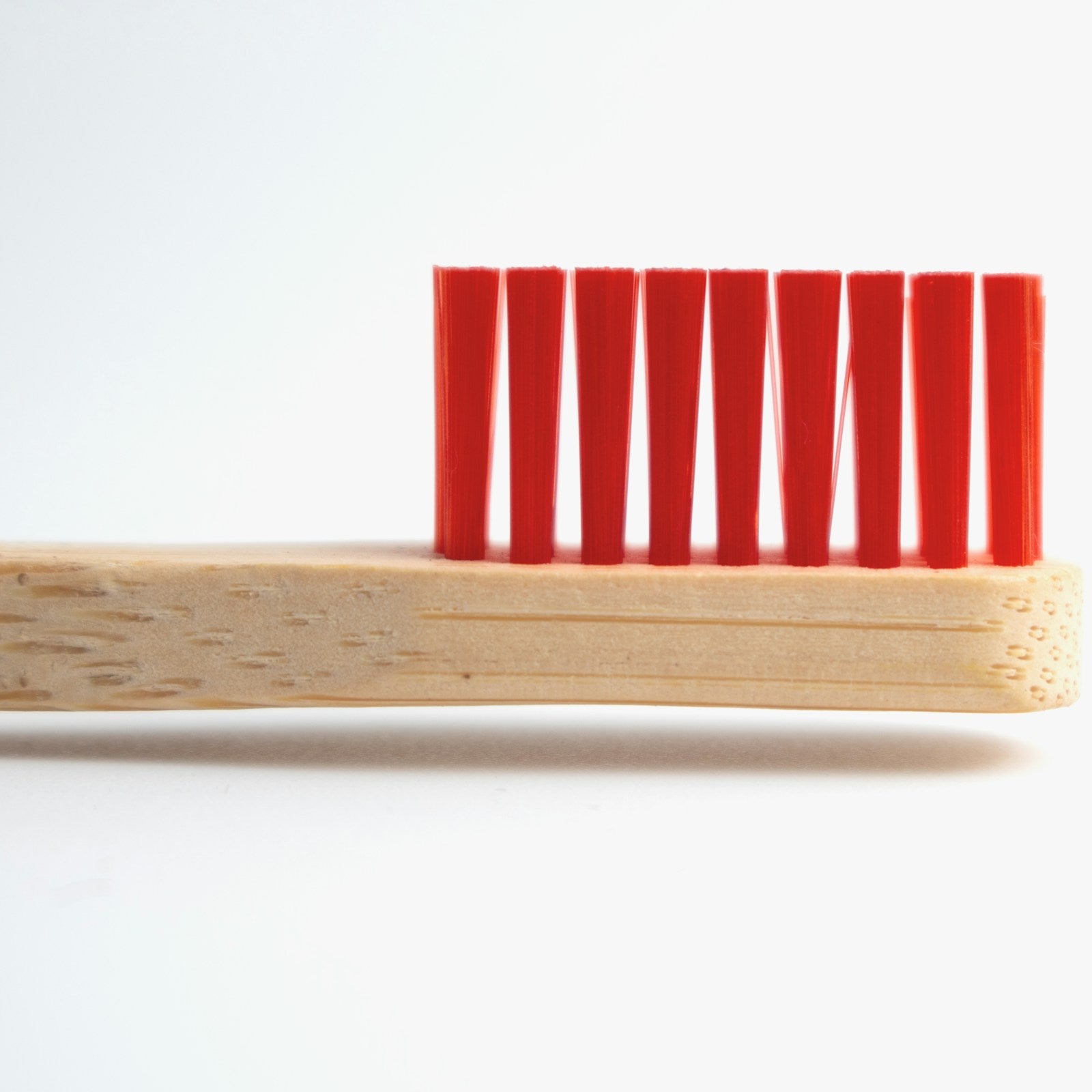 Kids bamboo toothbrush with red bristles, white background