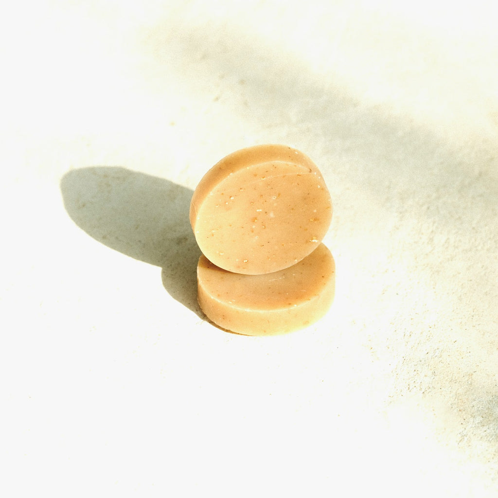 Two round solid shampoo bars stacked on a white studio background