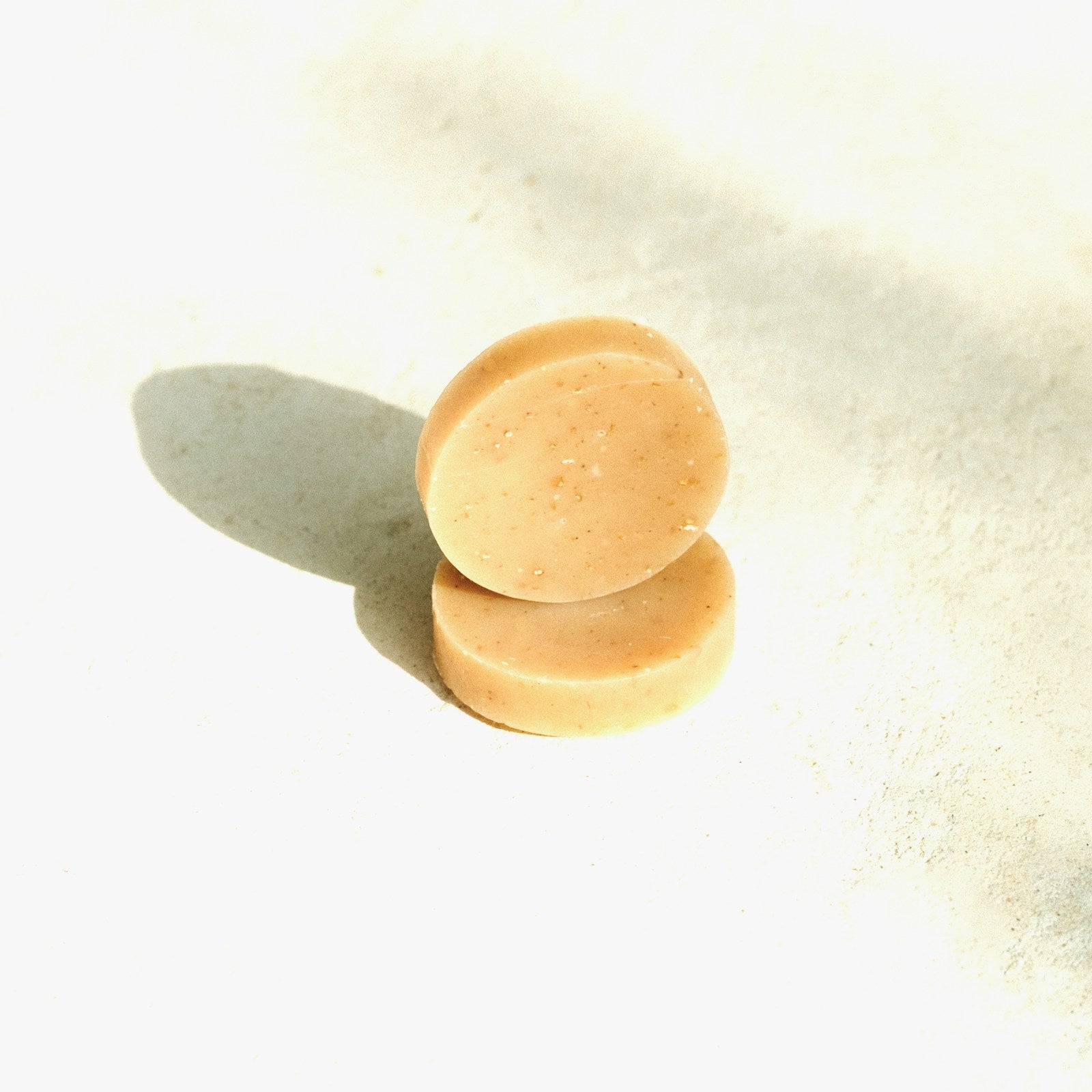 Two round solid shampoo bars stacked on a white studio background