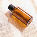 Amber glass sweet orange essential oil bottle on a light studio background