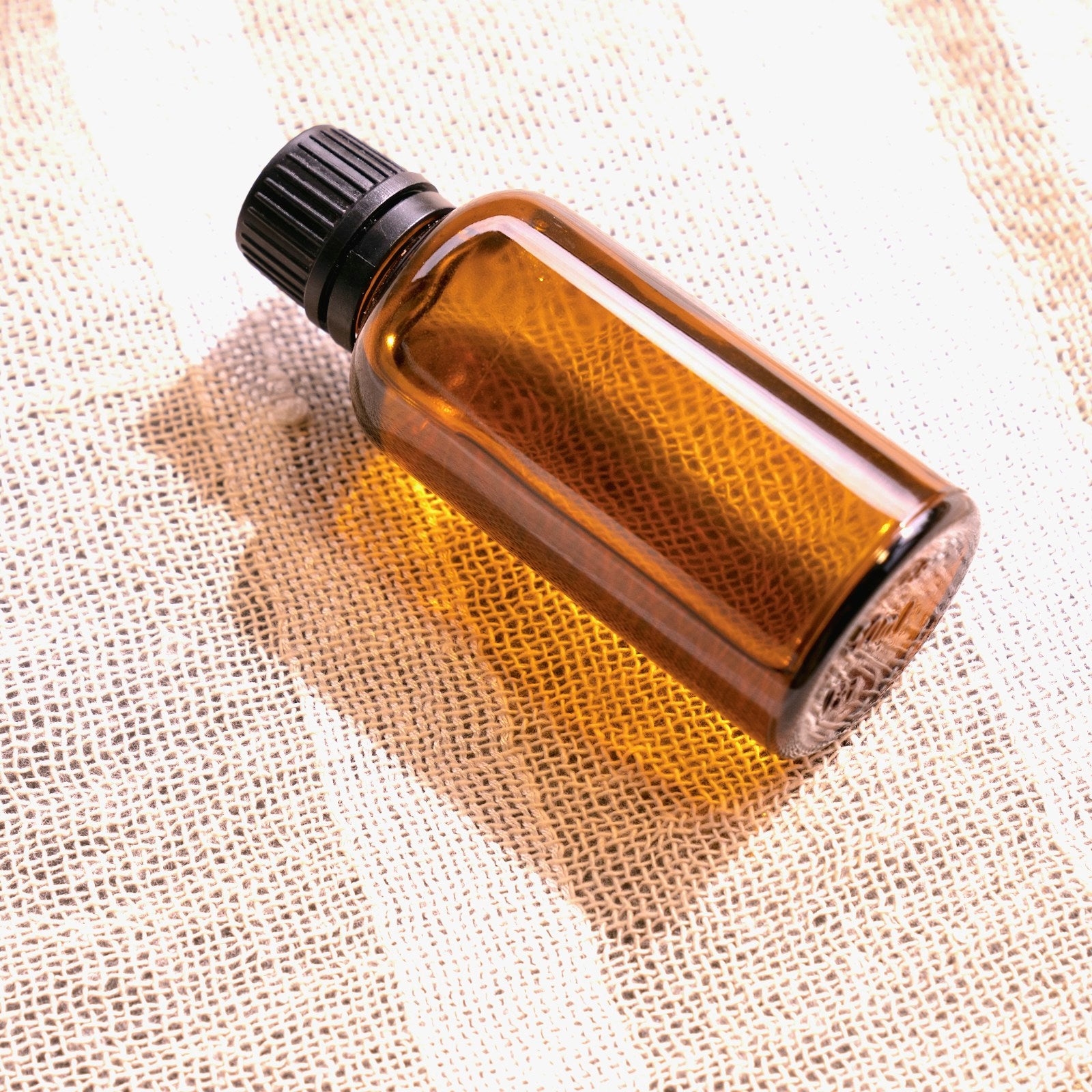 Amber glass sweet orange essential oil bottle on a light studio background
