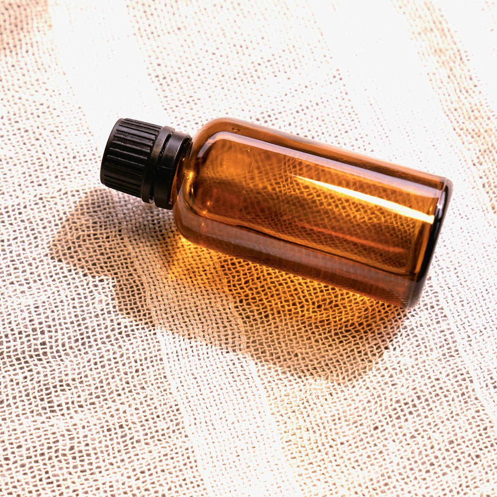 Amber glass essential oil bottle on a light studio background