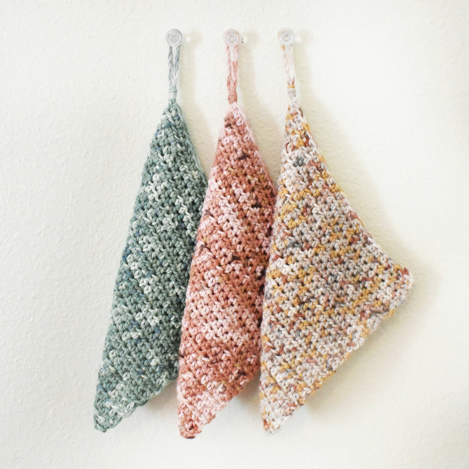 Set of three knitted cotton tawashi sponges on a white background