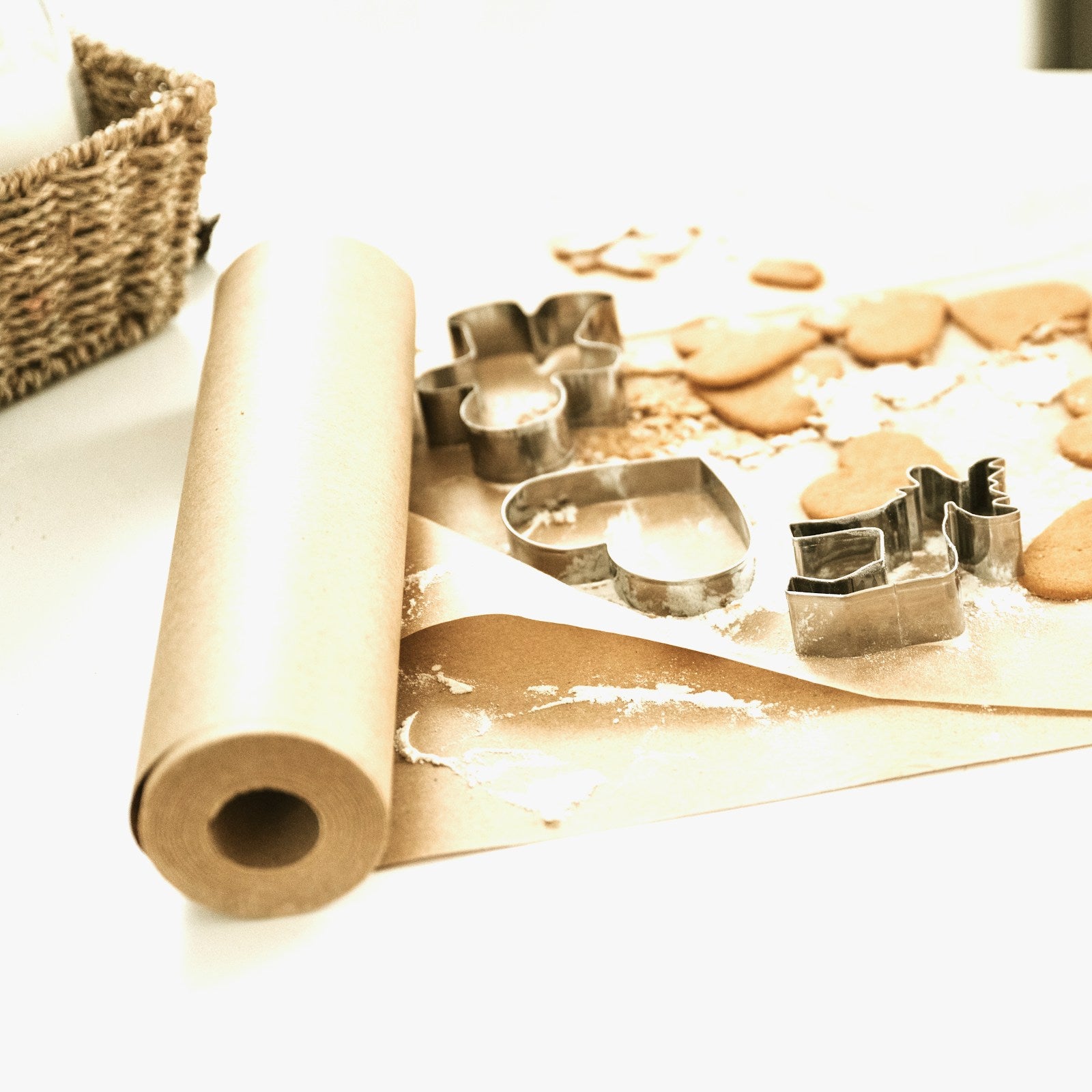 Roll of baking paper with biscuit cutters on a light background